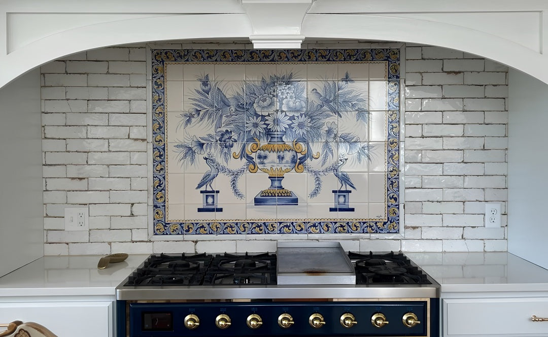 A decorative blue and white Portuguese ceramic tile backsplash featuring a central floral urn motif, installed behind a stainless steel gas range on a white brick kitchen wall.